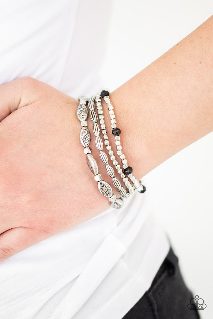 A collection of mismatched silver beads, silver cubes, and faceted black beads are threaded along four stretchy bands around the wrist for a colorful flair.  Sold as one set of four bracelets.
