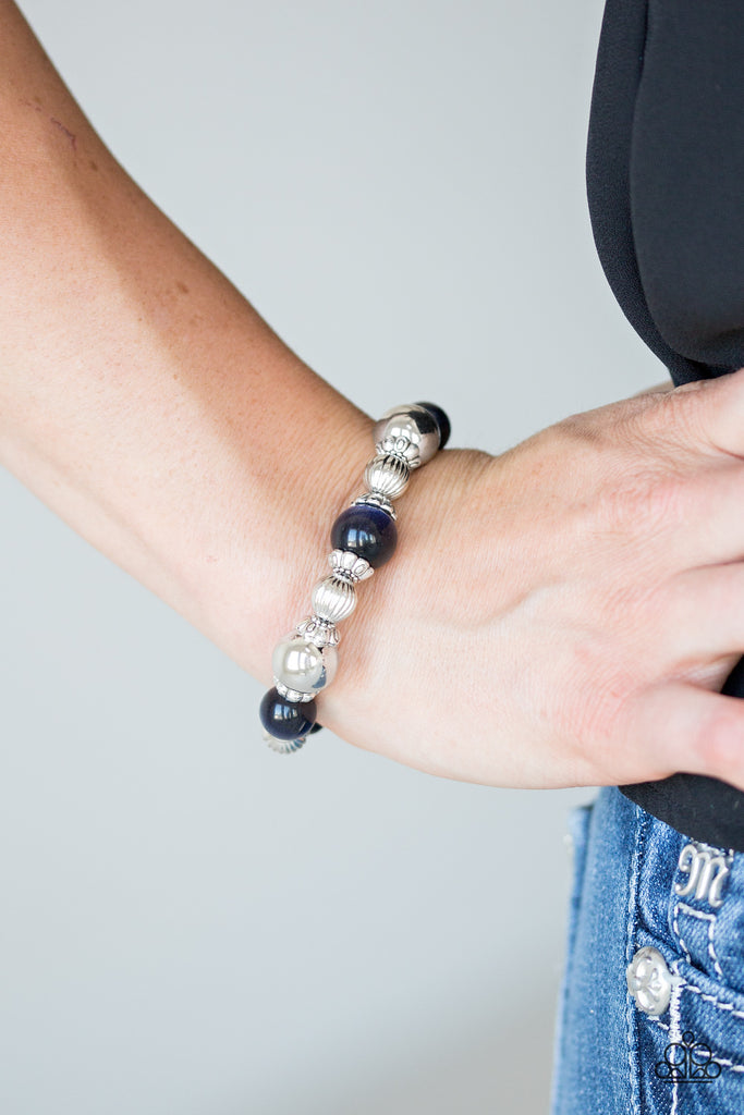 Glassy blue and ornate silver beads are threaded along a stretchy band around the wrist for a whimsical look.  Sold as one individual bracelet.