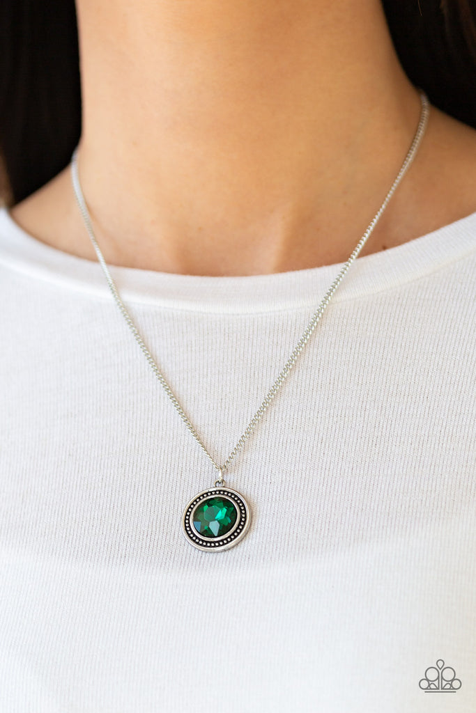 A glittery green gem is pressed into a studded silver frame, creating a glamorous pendant below the collar. Features an adjustable clasp closure.  Sold as one individual necklace. Includes one pair of matching earrings.  