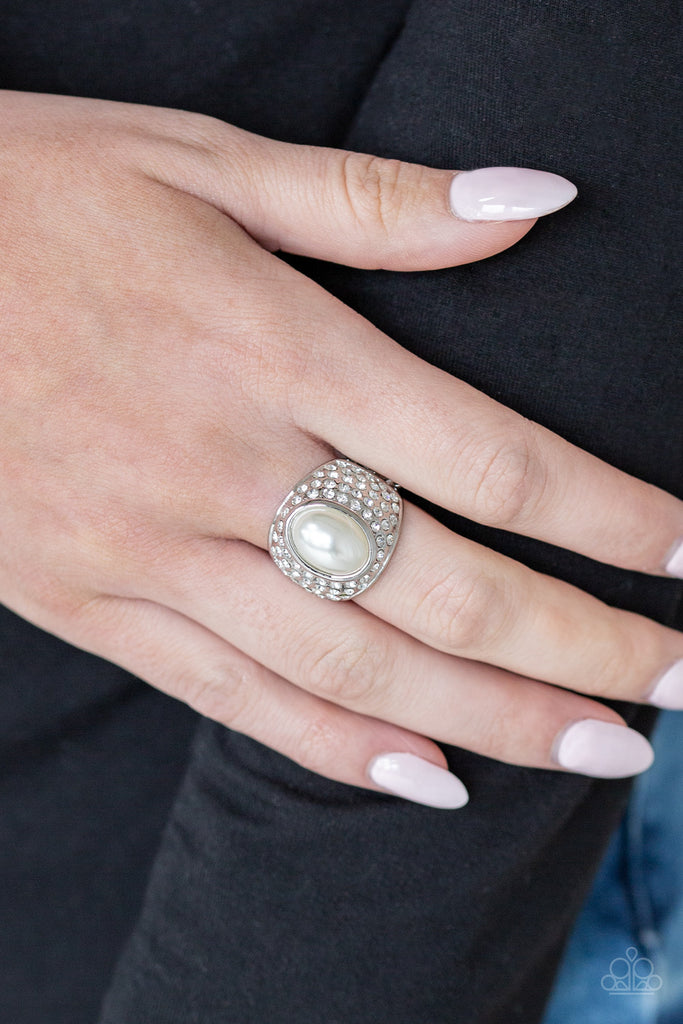 A pearly white bead is pressed into the center of a bold silver band radiating with countless white rhinestones, creating a dramatic statement piece atop the finger. Features a stretchy band for a flexible fit.  Sold as one individual ring.  