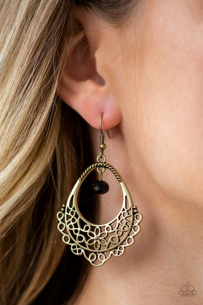 Glistening brass filigree swirls into a whimsical floral pattern on the bottom of an ornate teardrop frame. A black crystal-like bead swings from the top of the frame for a sparkling finish. Earring attaches to a standard fishhook fitting.  Sold as one pair of earrings.