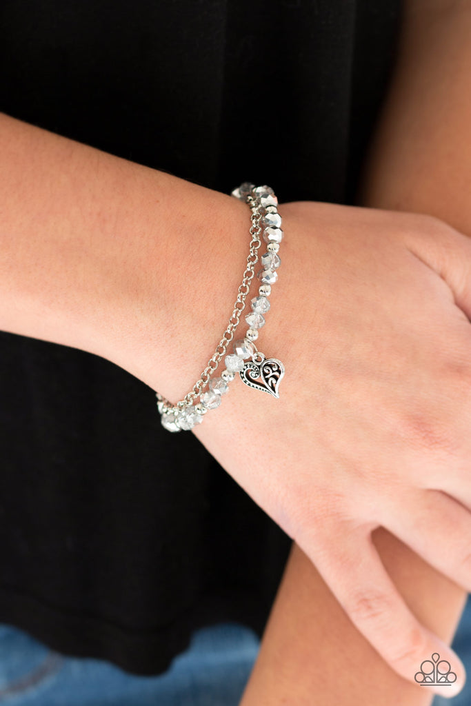 Dainty silver beads join a collection of glassy and metallic crystal-like beads around the wrist. Infused with a dainty silver chain, an ornate silver heart charm swings from the beaded strand for a romantic finish. Features an adjustable clasp closure.  Sold as one individual bracelet.