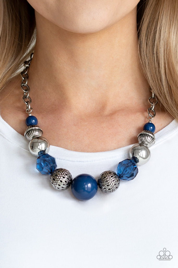 A collection of antiqued silver beads, glassy blue crystal-like beads, and oversized blue beads are threaded along an invisible wire below the collar. Textured in linear patterns, an antiqued silver chain attaches to the colorful compilation for a statement-making finish. Features an adjustable clasp closure.  Sold as one individual necklace. Includes one pair of matching earrings.