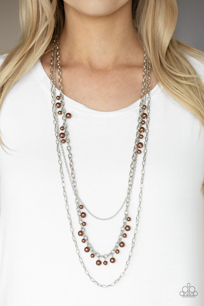 Three mismatched silver chains layer down the chest. Dainty brown pearls cascade down one silver chain, adding a flirty twist to the timeless pearl palette. Features an adjustable clasp closure.  Sold as one individual necklace. Includes one pair of matching earrings.  