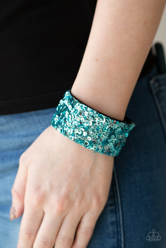 A collision of glittery rhinestones and sparkling blue sequins are encrusted along the front of a black suede band, creating blinding shimmer around the wrist. Features an adjustable snap closure.  Sold as one individual bracelet.  