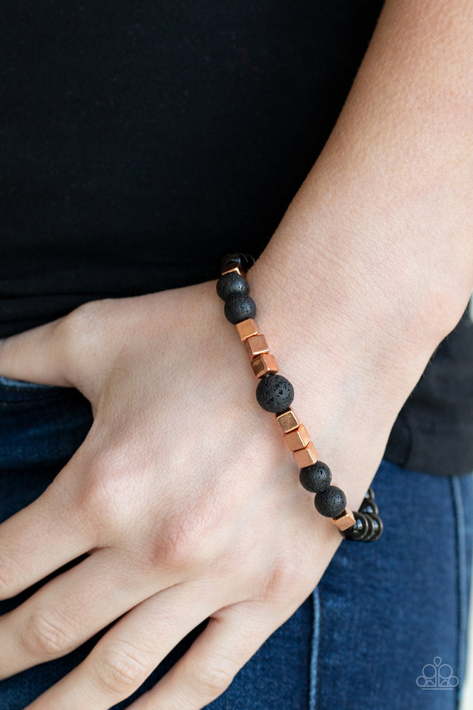 A collection of glassy black beads, earthy lava rock beads, and shimmery shiny copper cubes are threaded along a stretchy band around the wrist for a seasonal flair.  Sold as one individual bracelet.