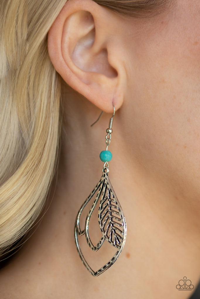 Featuring a hammered antiqued finish, feathery silver frames overlap inside of a silver teardrop frame. The whimsical frame swings from the bottom of a smooth turquoise stone bead for a seasonal finish. Earring attaches to a standard fishhook fitting.  Sold as one pair of earrings.