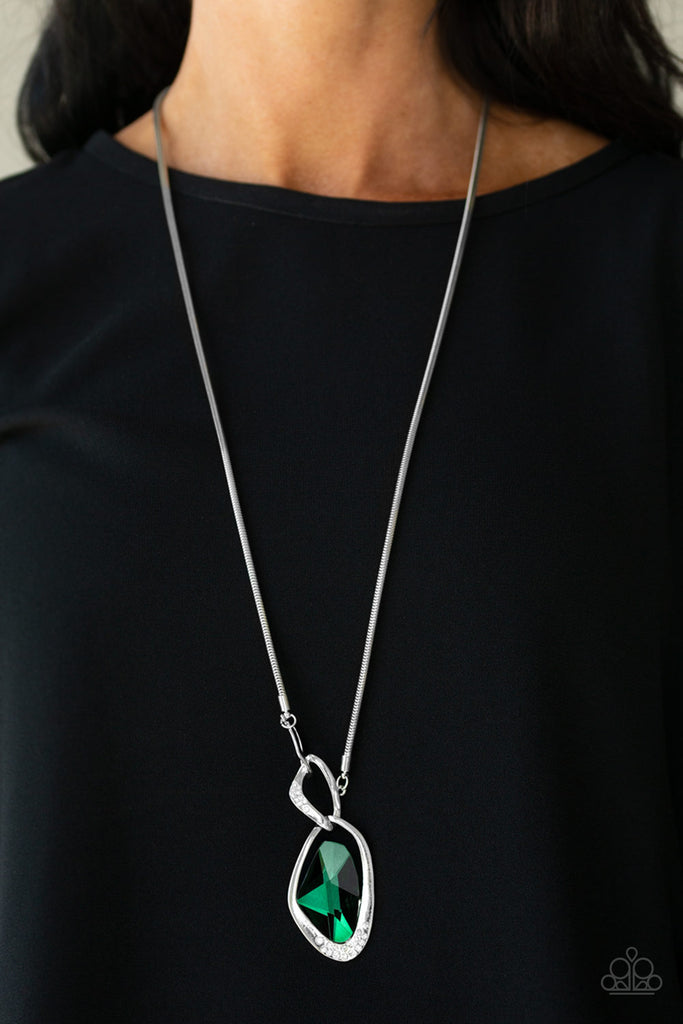A faceted green gem is nestled inside of a shimmery silver frame encrusted in dainty white rhinestones. The glittery pendant asymmetrically links with abstract silver frames at the bottom of a lengthened silver rounded snake chain for a modern look. Features an adjustable clasp closure.  Sold as one individual necklace. Includes one pair of matching earrings.  