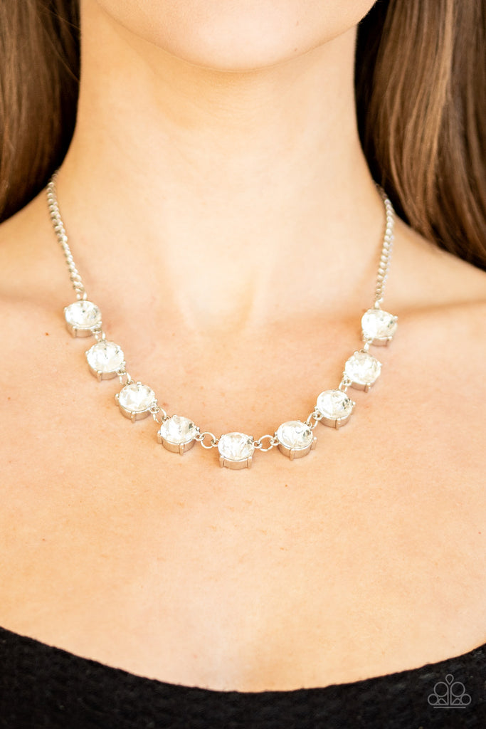 Featuring sleek silver fittings, a collection of oversized white rhinestones link below the collar for an icy look. Features an adjustable clasp closure.  Sold as one individual necklace. Includes one pair of matching earrings.