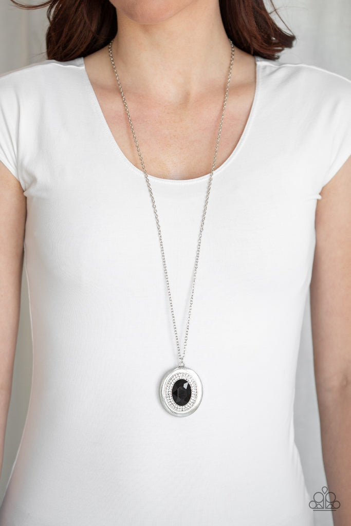 Encircled in rings of glassy white rhinestones, an oversized black gem is pressed into the center of a glistening silver frame, creating a glamorous pendant at the bottom of a lengthened silver chain. Features an adjustable clasp closure.  Sold as one individual necklace. Includes one pair of matching earrings.