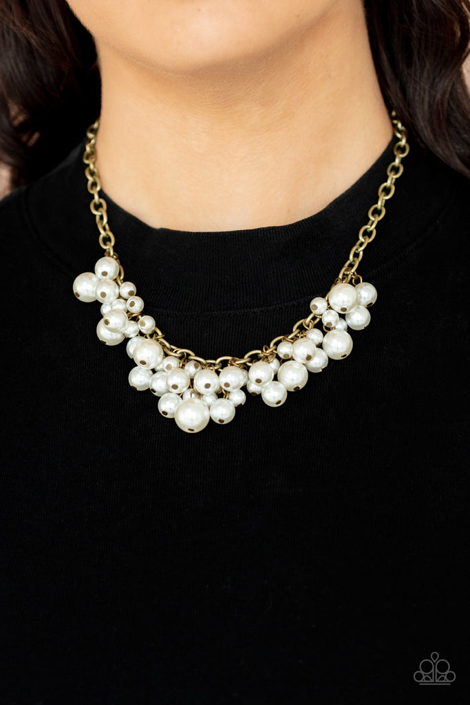 A bubbly collection of classic and oversized white pearls swing from the bottom of a bold brass chain, creating a dramatic fringe below the collar. Features an adjustable clasp closure.  Sold as one individual necklace. Includes one pair of matching earrings.