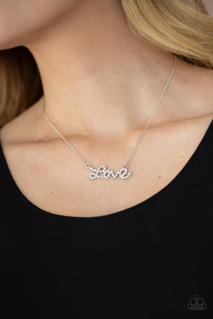 Encrusted in glassy white rhinestones, the word, "love," connects to a dainty silver chain, creating a flirty pendant below the collar. Features an adjustable clasp closure.  Sold as one individual necklace. Includes one pair of matching earrings.
