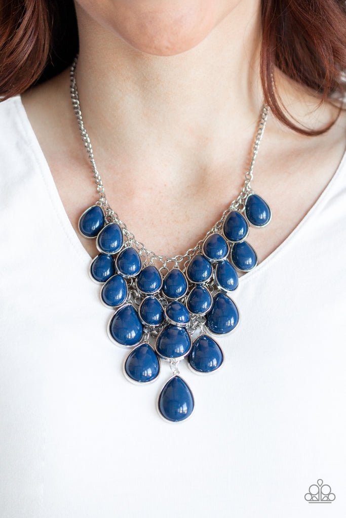 Tinted in the classic rich hue of Evening Blue, polished blue teardrops gradually increase in size as they trickle along rows of interconnected mesh chain. The robust beads drip into a tapered shape, creating a dramatic fringe below the collar. Features an adjustable clasp closure.  Sold as one individual necklace. Includes one pair of matching earrings