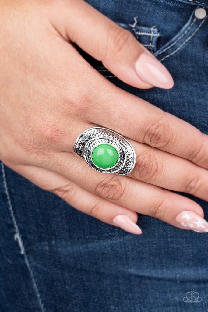 A neon green bead is pressed into the center of a stacked silver frame radiating with sunburst patterns, creating a flamboyant centerpiece. Features a stretchy band for a flexible fit.  Sold as one individual ring.