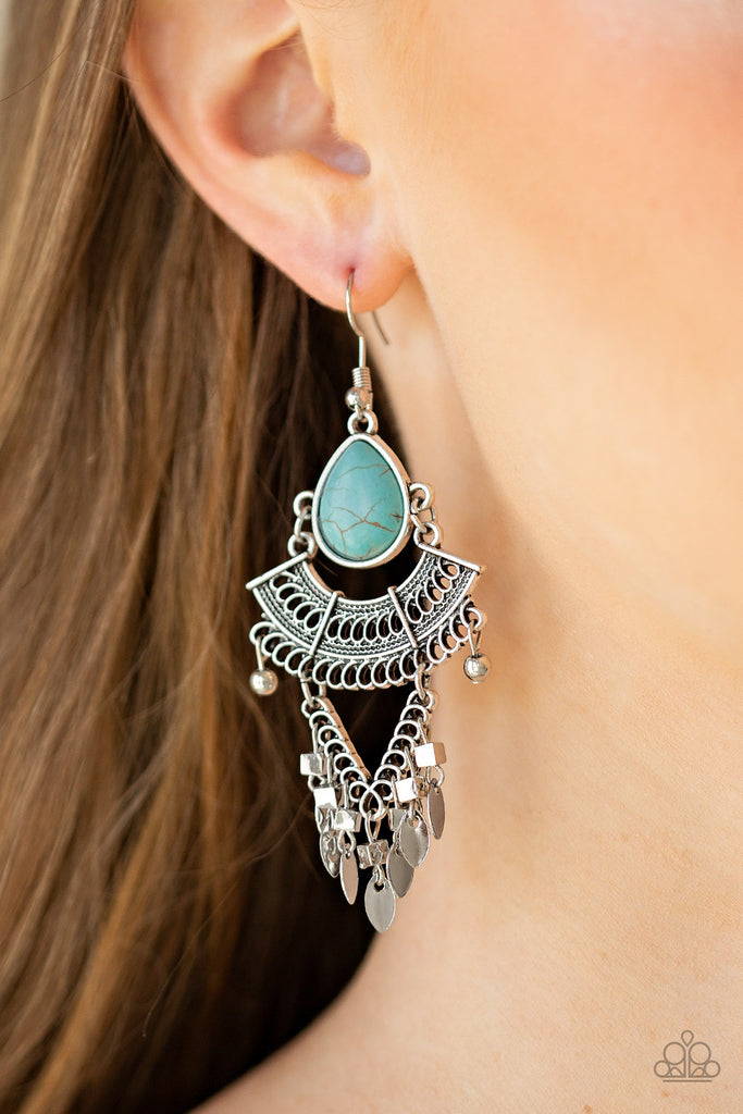 A refreshing teardrop turquoise stone gives way to a stack of linked silver frames featuring bold tribal inspired patterns. Infused with glistening silver cube beads, a fringe of flat silver beads swing from the bottom for a flirtatiously wanderlust finish. Earring attaches to a standard fishhook fitting.  Sold as one pair of earrings.