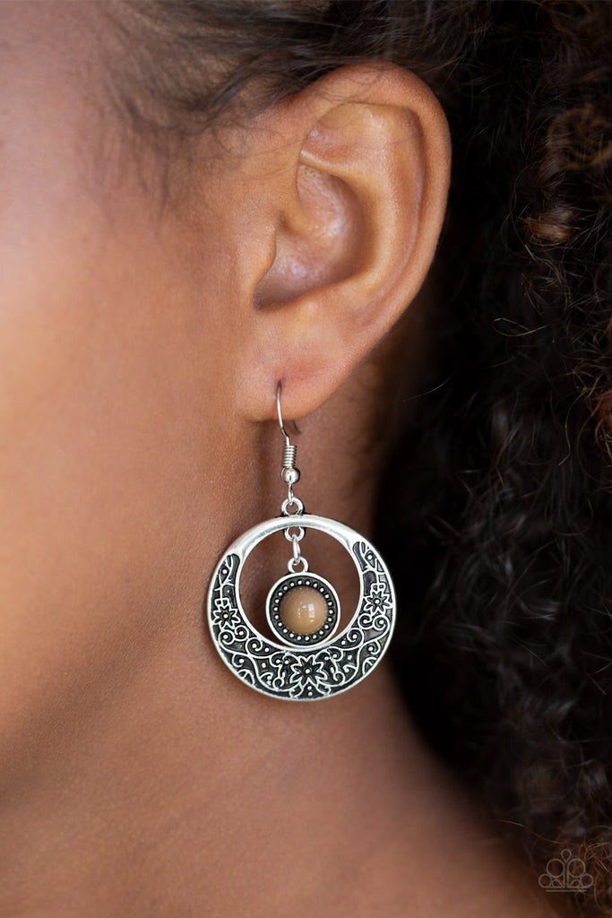 A flirty brown bead swings from the top of a shimmery silver hoop featuring floral detail for a seasonal look. Earring attaches to a standard fishhook fitting.  Sold as one pair of earrings.