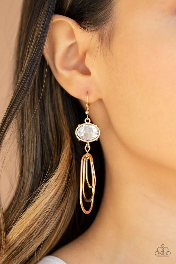 Oval shaped gold frames drip from the bottom of an oversized white rhinestone gem, creating a rippling fringe. Earring attaches to a standard fishhook fitting.  Sold as one pair of earrings.