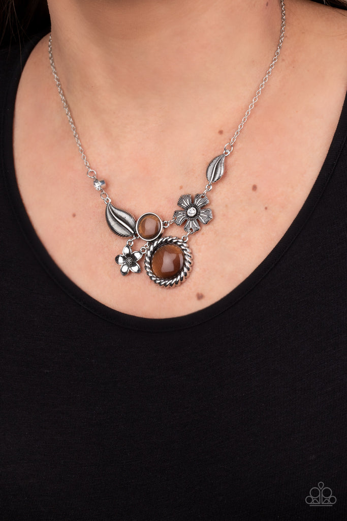 Dotted with brown cat's eye stones and dainty white rhinestones, mismatched floral frames connect below the collar for a whimsical look. Features an adjustable clasp closure.  Sold as one individual necklace. Includes one pair of matching earrings.  