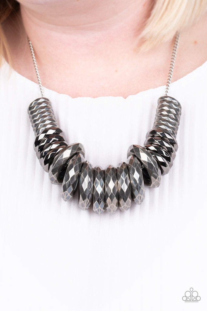 Gradually increasing in size, a collision of faceted silver and gunmetal rings slide along a classic silver chain below the collar for a bold industrial look. Features an adjustable clasp closure.  Sold as one individual necklace. Includes one pair of matching earrings.