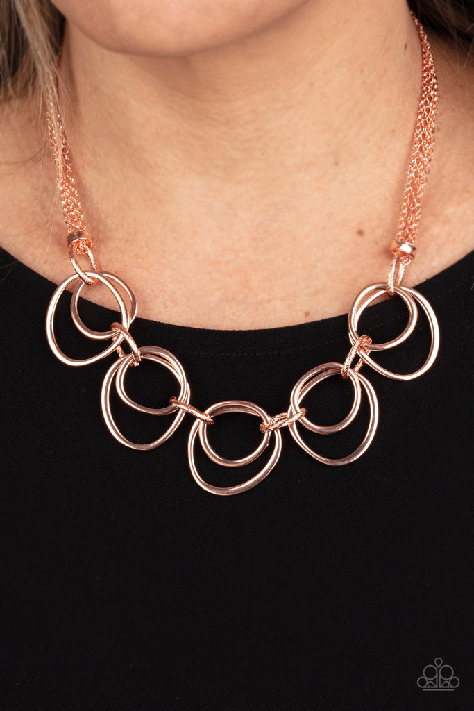 Infused with decorative shiny copper links, an asymmetrical assortment of shiny copper rings delicately link below the collar for a refined flair. Features an adjustable clasp closure.  Sold as one individual necklace. Includes one pair of matching earrings.  