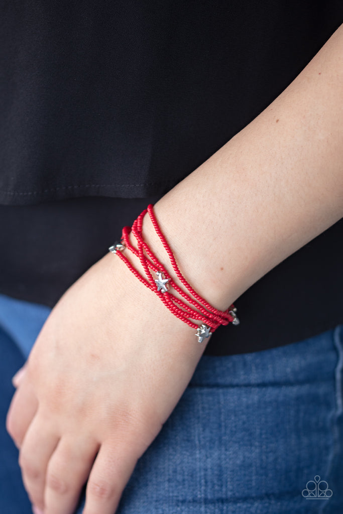 Dotted with shiny silver star charms, a colorful assortment of dainty red seed beads are threaded along stretchy bands, creating stellar layers.  Sold as one set of five bracelets.