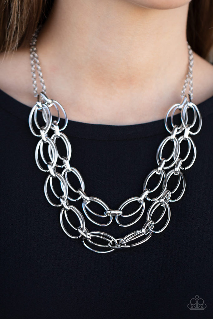 Varying in size, pairs of oval links connect into two bold layers below the collar for a gritty industrial look. Features an adjustable clasp closure.  Sold as one individual necklace. Includes one pair of matching earrings.  