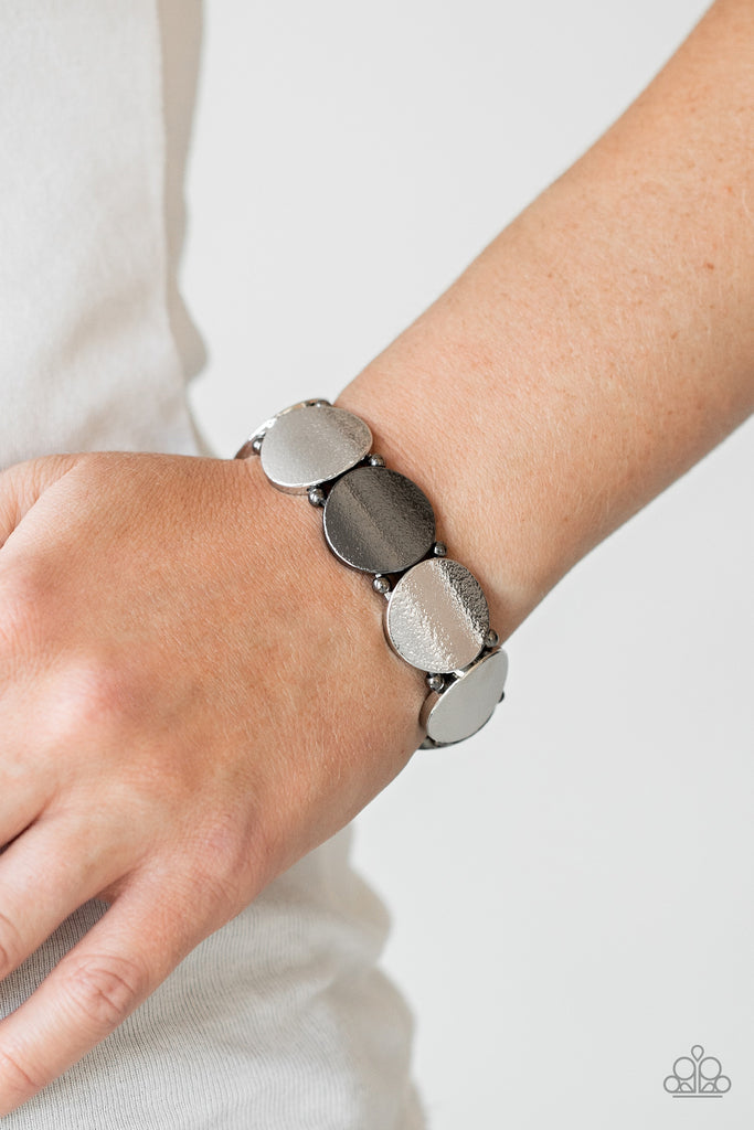 Infused with pairs of dainty gunmetal beads, delicately hammered gunmetal and silver discs slide along a stretchy band around the wrist for a hint of industrial flavor.  Sold as one individual.  
