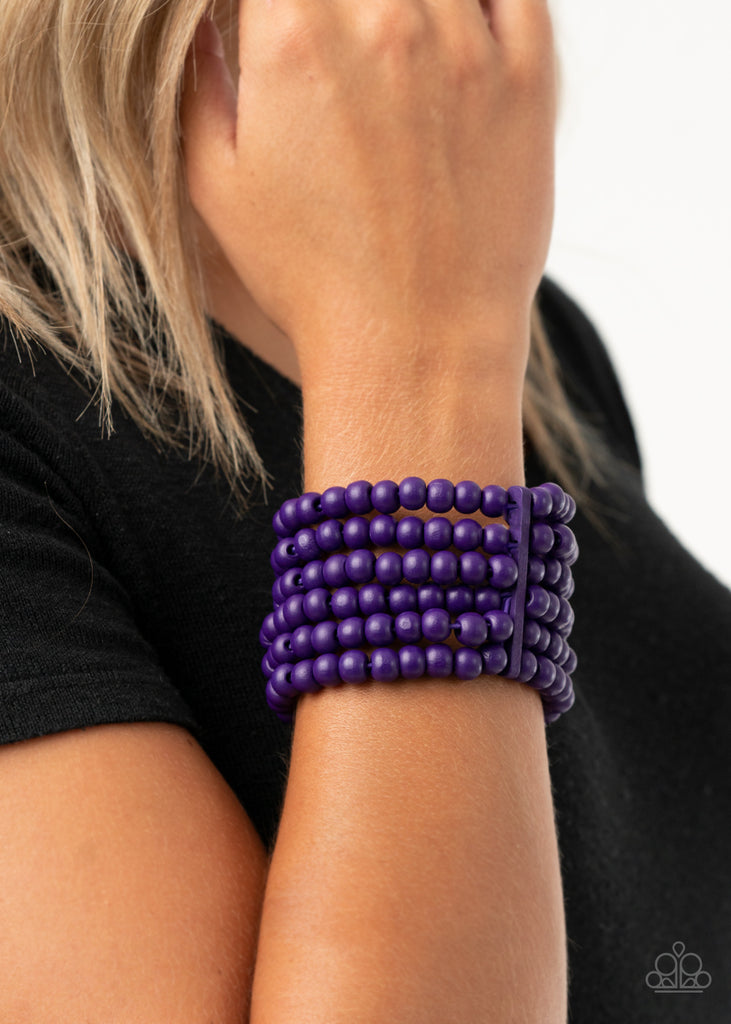 Held in place with rectangular wooden fittings, a collection of vivacious purple wooden beads are threaded along stretchy bands around the wrist, creating colorful layers.  Sold as one individual bracelet.