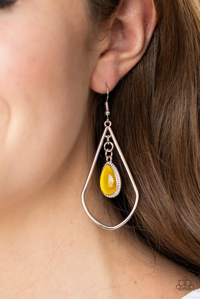 A dewy yellow cat's eye stone teardrop frame swings from the top of an angular silver teardrop, creating a whimsical lure. Earring attaches to a standard fishhook fitting.  Sold as one pair of earrings.