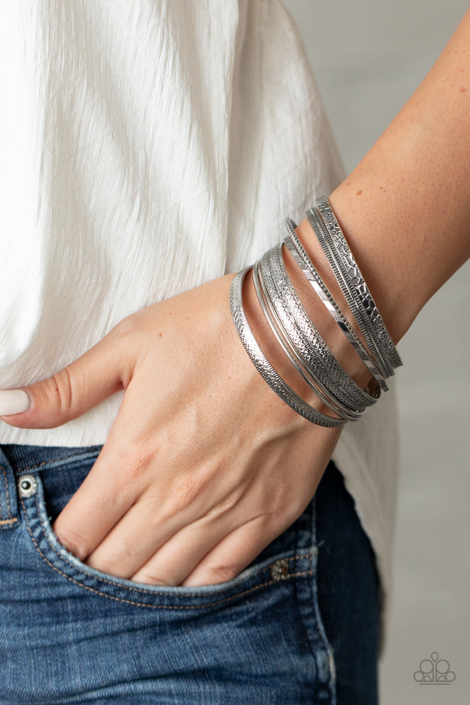 Featuring smooth, studded, hammered, and textured finishes, a mismatched collection of antiqued silver bangles stack across the wrist for a seasonal look.  Sold as one set of nine bracelets.