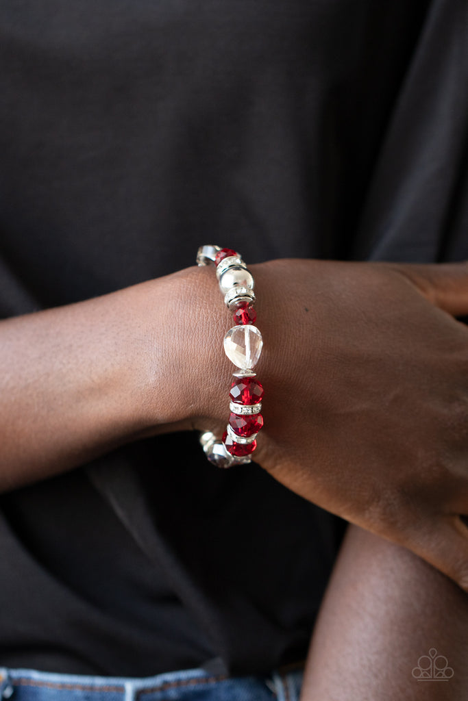 A glamorous collection of white rhinestone encrusted rings, silver beads, glassy white gems, and glittery red crystal-like beads are threaded along a stretchy band around the wrist for a refined flair.  Sold as one individual bracelet.