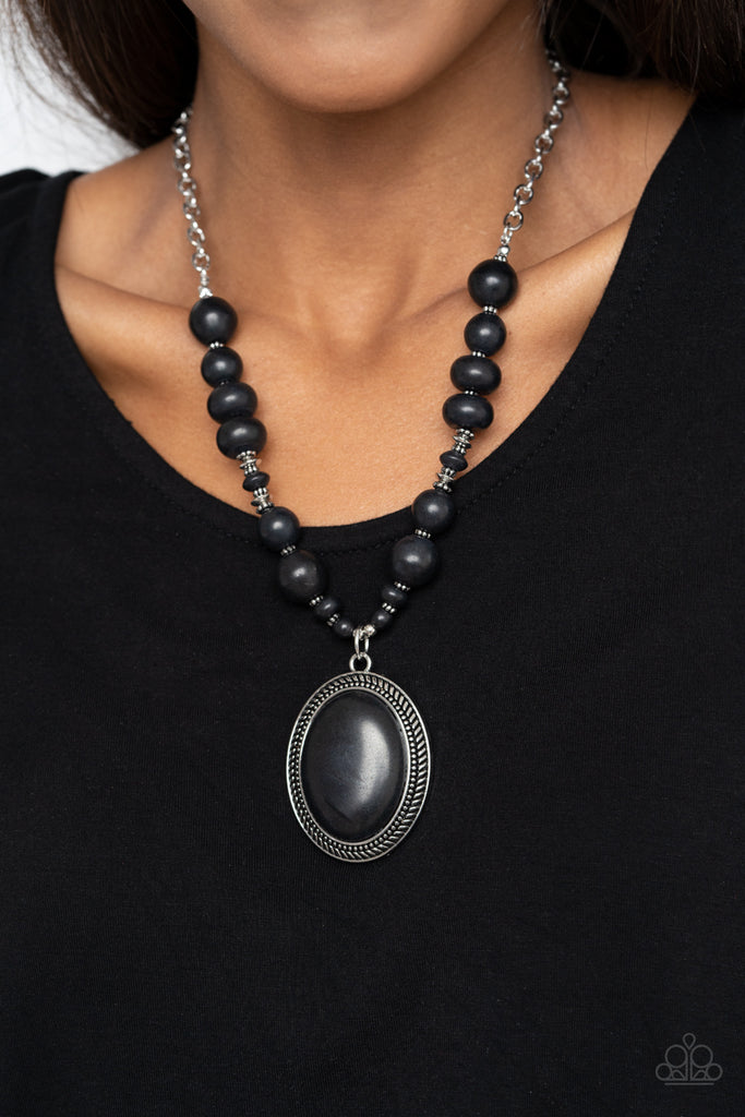 A mismatched collection of black stone beads and antiqued silver accents are threaded along an invisible wire attached to a shimmery silver chain. Bordered in a metallic rope-like silver frame, a dramatically oversized black stone pendant swings from the earthy compilation for an authentically artisan finish. Features an adjustable clasp closure.  Sold as one individual necklace. Includes one pair of matching earrings.
