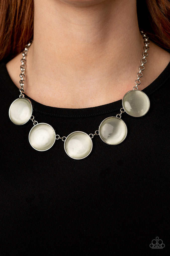 Featuring sleek silver fittings, a collection of round white cat's eye stone pendants link below the collar for a colorfully ethereal look. Features an adjustable clasp closure.  Sold as one individual necklace. Includes one pair of matching earrings.