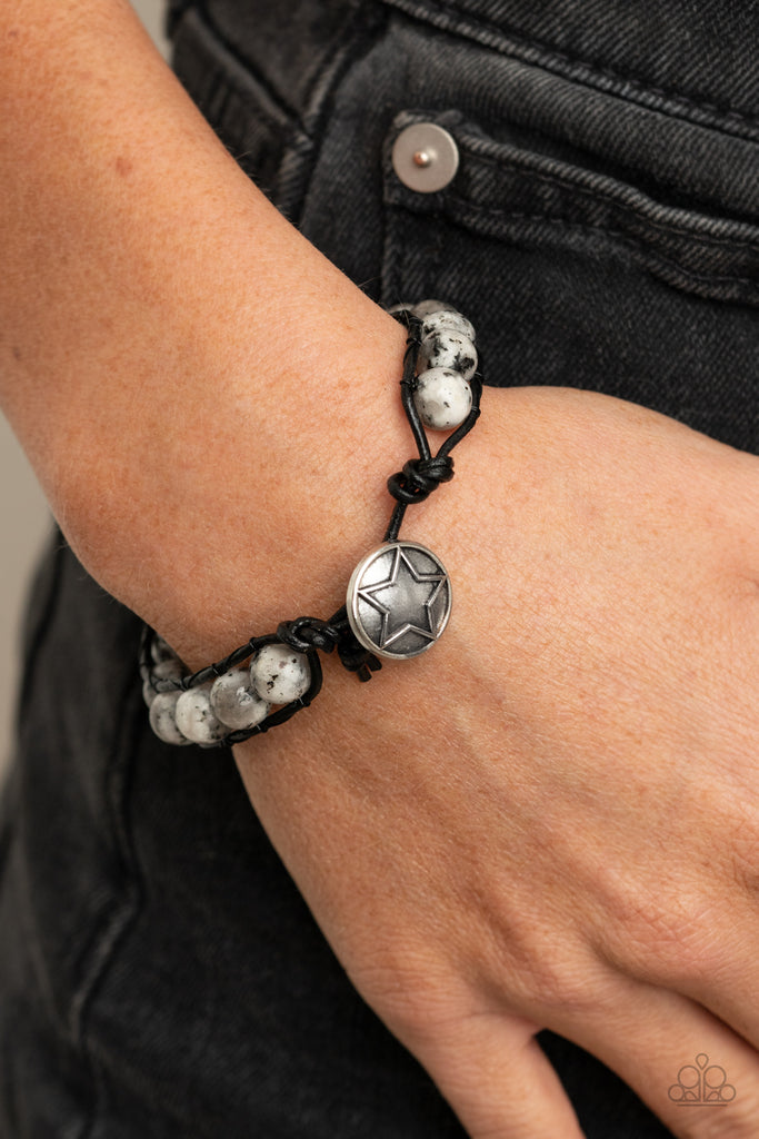 Infused with a decorative silver star embossed button, speckled white stones are threaded in place between two dainty black cords around the wrist for a seasonal fashion. Features a button loop closure.  Sold as one individual bracelet.