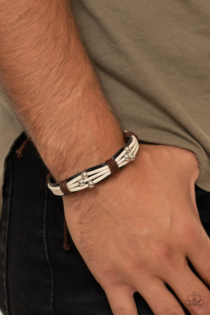 Shiny silver beads slide along white cording that has been knotted in place with brown cording across the front of a black leather band, creating a rustic look around the wrist. Features an adjustable sliding knot closure.  Sold as one individual bracelet.
