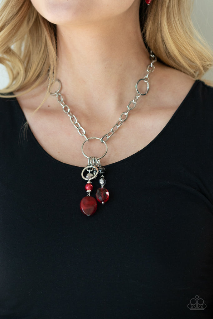 A glittery compilation of faceted, smooth, and pearly red, black, and silver beaded charms swing from the bottom of a silver ring that attaches to a chunky silver chain below the collar for a colorfully charming look. Features an adjustable clasp closure.  Sold as one individual necklace. Includes one pair of matching earrings.  