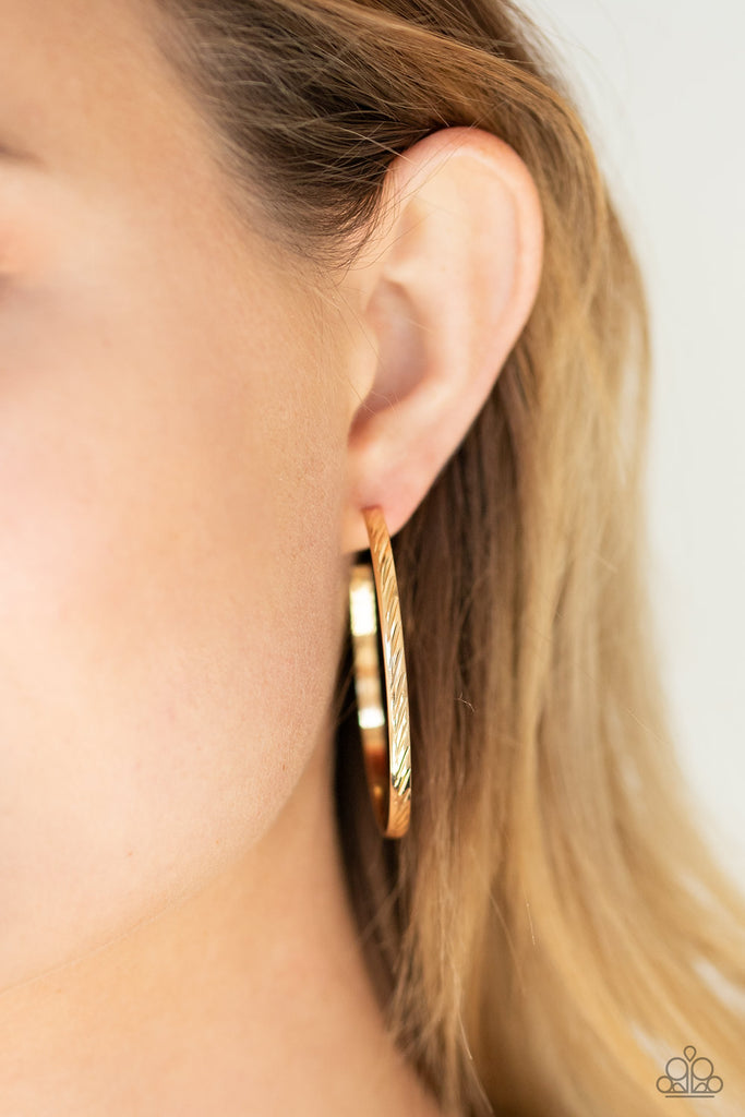 Etched in slanting linear detail, a classic gold hoop curls around the ear for a chic and casual look. Earring attaches to a standard post fitting. Hoop measures approximately 1 3/4" in diameter.  Sold as one pair of hoop earrings.  