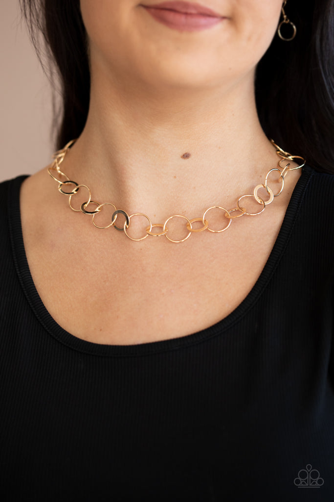 Dainty gold hoops and rings delicately link into a chic chain, creating simplistic shimmer below the collar. Features an adjustable clasp closure.  Sold as one individual necklace. Includes one pair of matching earrings.