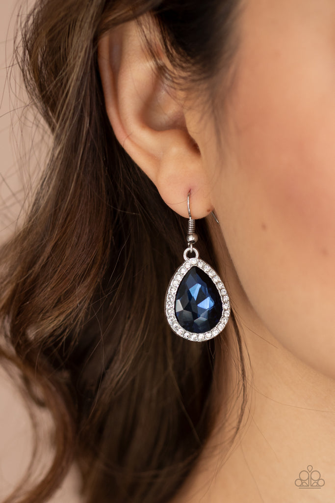 A blue teardrop gem is pressed into the center of a silver teardrop frame encrusted in glassy white rhinestones, creating dramatic sparkle. Earring attaches to a standard fishhook fitting.  Sold as one pair of earrings.