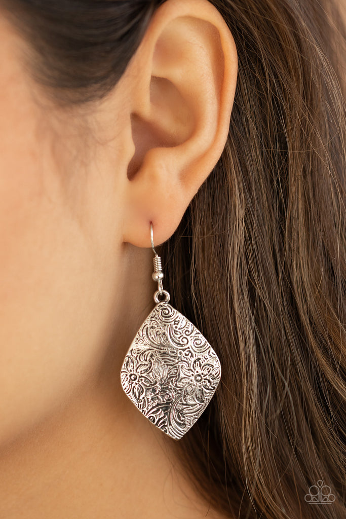 Brushed in an antiqued shimmer, the front of a silver frame is embossed in a whimsical floral pattern for a seasonal flair. Earring attaches to a standard fishhook fitting.  Sold as one pair of earrings.