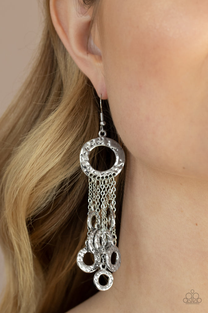 Attached to dainty silver chains, a fringe of hammered silver rings swings from the bottom of a matching hammered ring for a noise-making statement. Earring attaches to a standard fishhook fitting.  Sold as one pair of earrings.