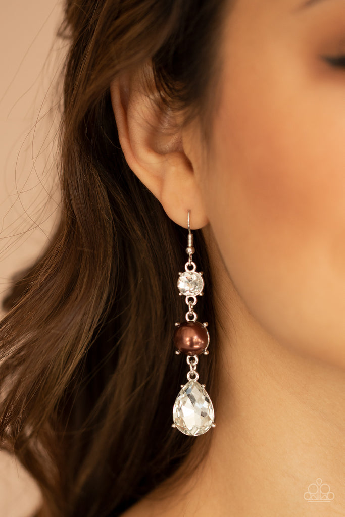 An oversized white teardrop gem swings from the bottom of a stacked pearly brown bead and classic white rhinestone, creating a timeless lure. Earring attaches to a standard fishhook fitting.  Sold as one pair of earrings.