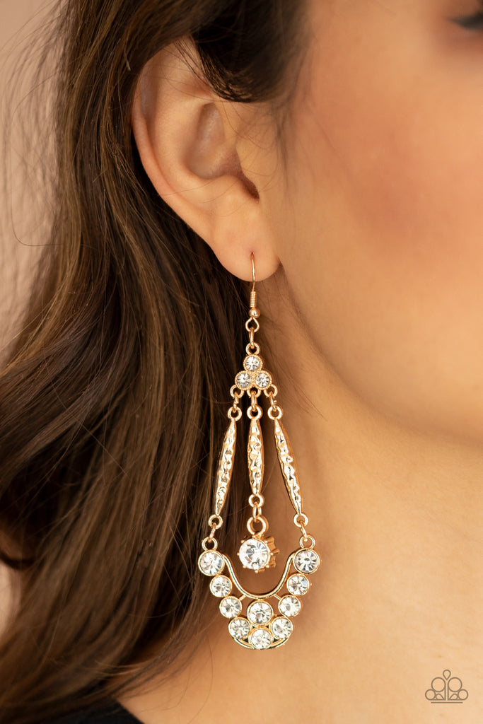 A trio of glassy white rhinestones gives way to hammered gold bars attached to a bubbly white rhinestone encrusted frame. Attached to a matching gold bar, a solitaire white rhinestone swings from the center, creating a timeless chandelier. Earring attaches to a standard fishhook fitting.  Sold as one pair of earrings.  