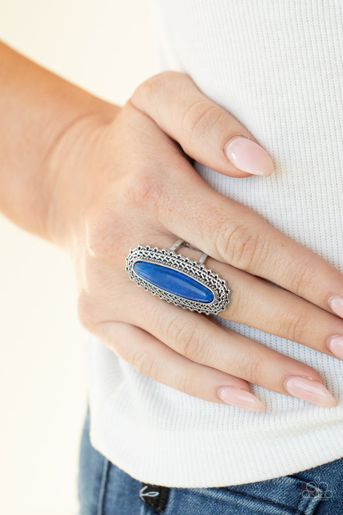 An oblong blue stone adorns the center of an elongated silver frame featuring mismatched silver textures for a bold artisan look. Features a stretchy band for a flexible fit.  Sold as one individual ring.