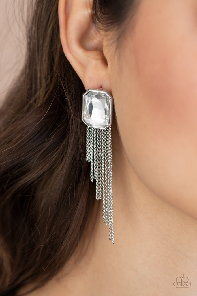 Tapered silver chains stream from the bottom of an oversized white emerald cut gem, creating a regal fringe. Earring attaches to a standard post fitting.  Sold as one pair of post earrings.