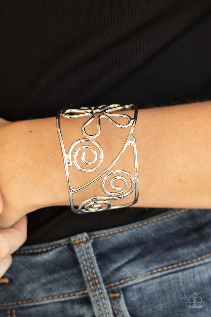 Shiny silver wire bends and curls into groovy floral and swirl frames, coalescing into a psychedelic cuff around the wrist.  Sold as one individual bracelet.