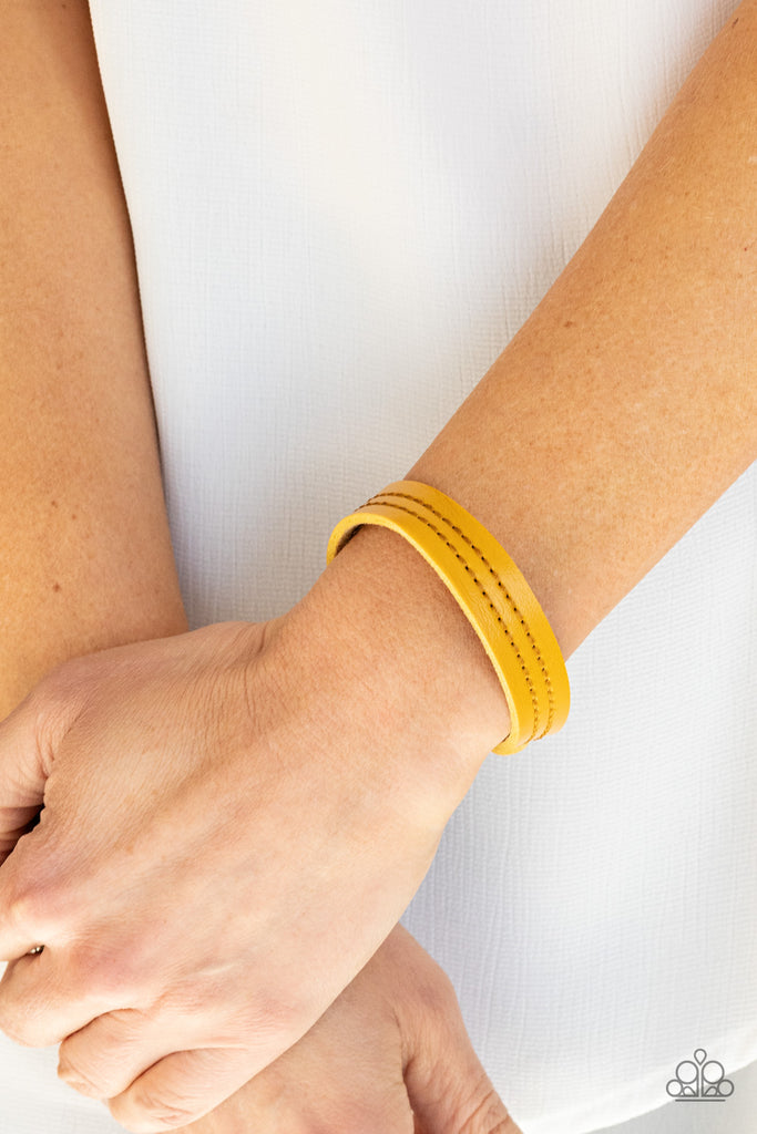 The front of a dainty yellow leather band is stitched in two linear rows, creating a colorfully rustic centerpiece around the wrist. Features an adjustable snap closure.  Sold as one individual bracelet.  