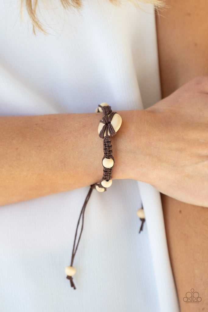 Infused with a wooden button-like centerpiece, pieces of earthy brown cording delicately knot wooden beads in place around the wrist for a homespun braided look. Features an adjustable sliding knot closure.  Sold as one individual bracelet.