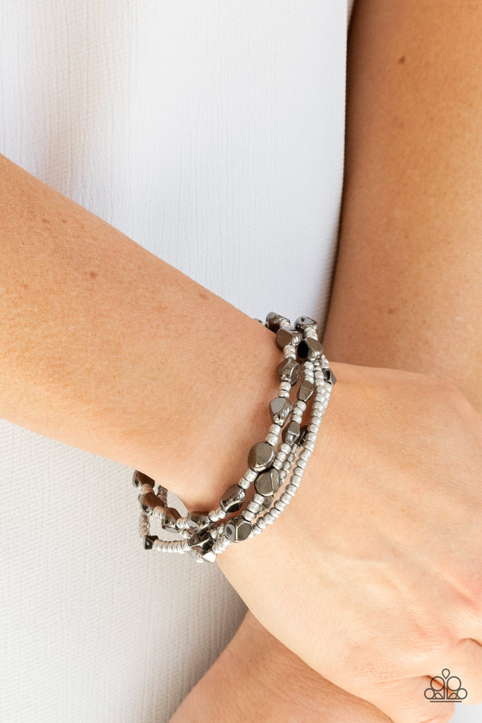 A shimmery collection of dainty silver seed beads and faceted gunmetal accents are threaded along stretchy bands around the wrist, creating glistening layers.  Sold as one set of four bracelets.  