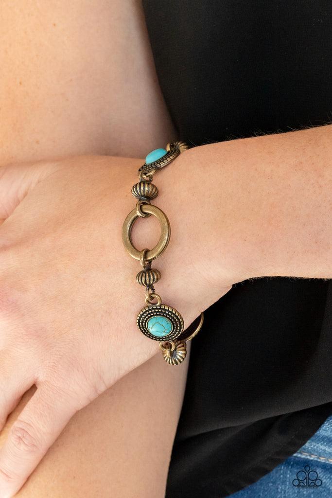 Featuring an airy brass hoop centerpiece, a rustic collection of brass beads and turquoise stone dotted brass frames delicately link around the wrist for a seasonal look. Features an adjustable clasp closure.  Sold as one individual bracelet.